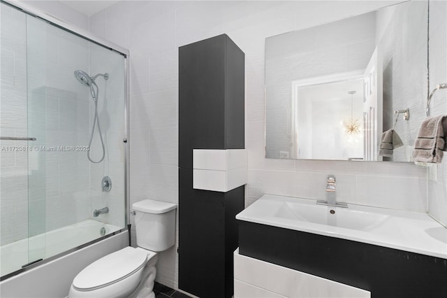 full bathroom featuring tasteful backsplash, bath / shower combo with glass door, toilet, vanity, and tile walls