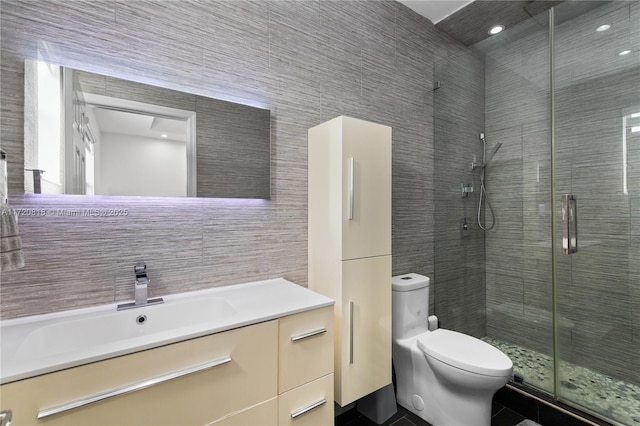 bathroom with walk in shower, tile patterned flooring, toilet, vanity, and tile walls