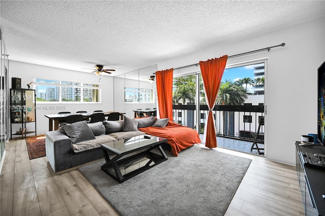 living room with ceiling fan, light hardwood / wood-style flooring, and a textured ceiling