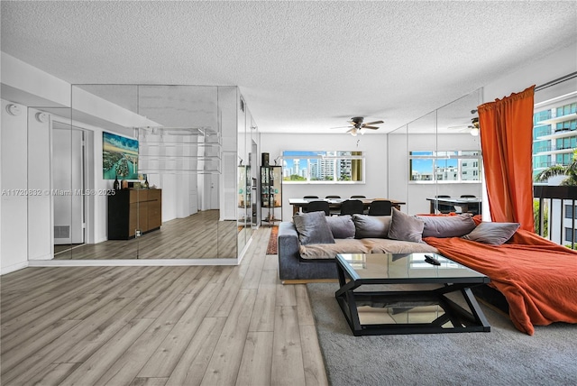 living room featuring hardwood / wood-style floors, a textured ceiling, ceiling fan, and a healthy amount of sunlight