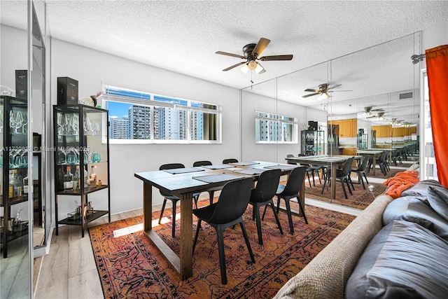 dining area featuring ceiling fan, light hardwood / wood-style flooring, and a textured ceiling