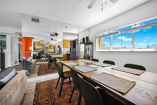 dining room with ceiling fan, light hardwood / wood-style floors, and a textured ceiling