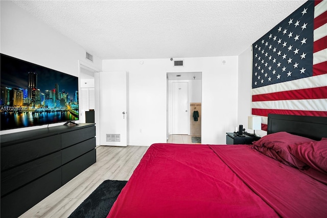 bedroom with light hardwood / wood-style floors and a textured ceiling