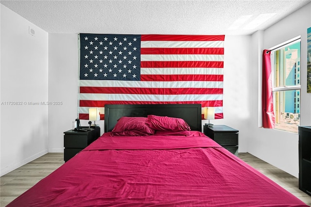 bedroom featuring multiple windows, a textured ceiling, and hardwood / wood-style flooring