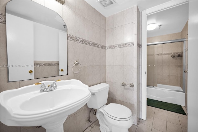 full bathroom with tile patterned floors, sink, combined bath / shower with glass door, and tile walls