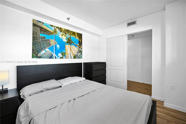 bedroom featuring dark hardwood / wood-style flooring and a textured ceiling