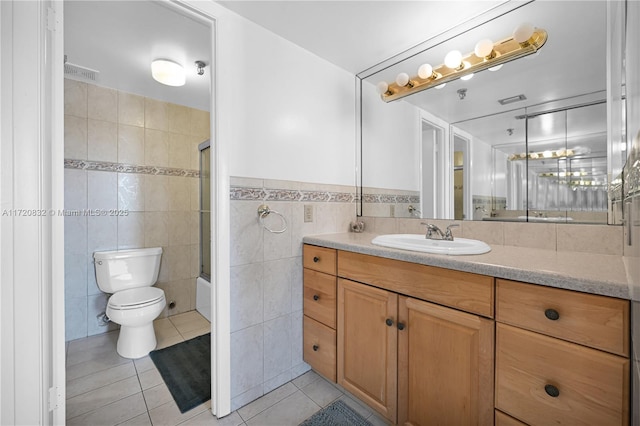 full bathroom with combined bath / shower with glass door, vanity, tile walls, tile patterned flooring, and toilet