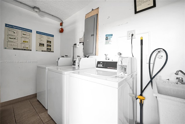 clothes washing area with washing machine and clothes dryer, electric panel, light tile patterned flooring, and a textured ceiling