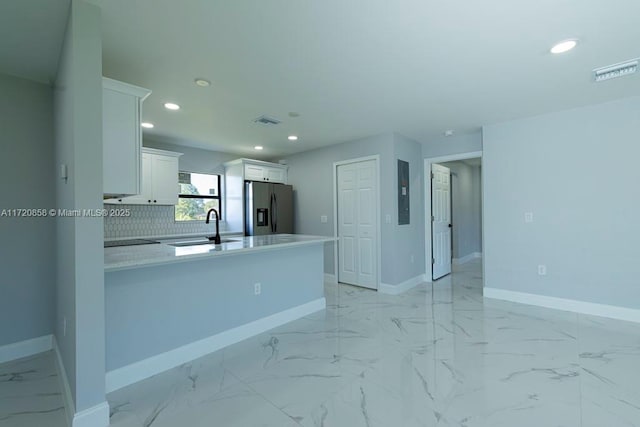 kitchen with kitchen peninsula, decorative backsplash, sink, stainless steel fridge with ice dispenser, and white cabinetry