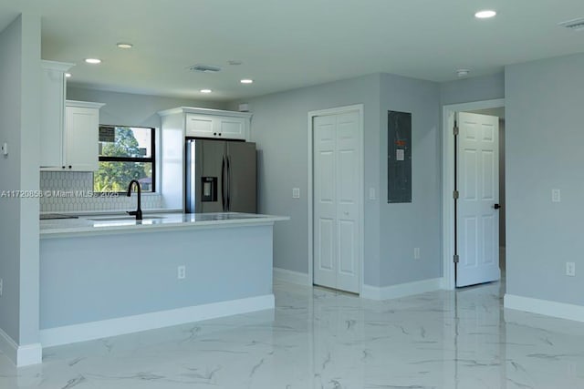 kitchen with electric panel, sink, stainless steel fridge, white cabinetry, and kitchen peninsula