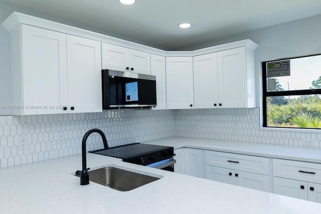 kitchen with light stone countertops, sink, white cabinets, and appliances with stainless steel finishes