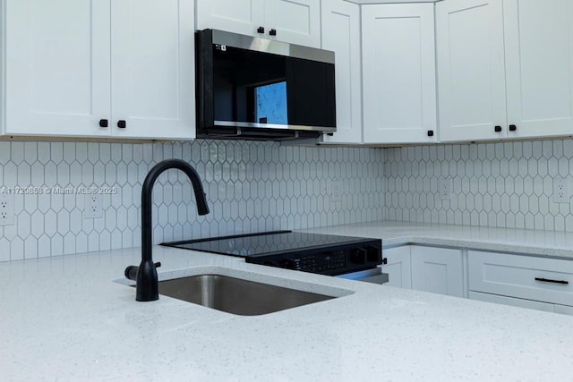 kitchen with light stone counters, white cabinetry, and tasteful backsplash