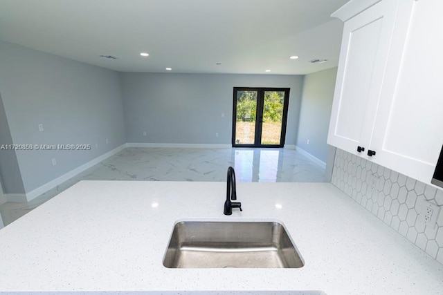 kitchen with white cabinets, light stone countertops, and sink