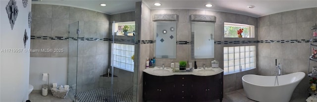 bathroom featuring plenty of natural light, vanity, tile walls, and shower with separate bathtub