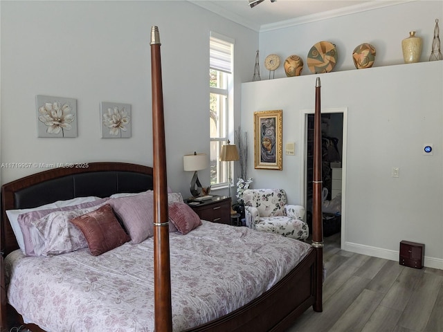 bedroom with hardwood / wood-style flooring, a spacious closet, crown molding, and a closet