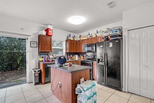 kitchen with backsplash, a textured ceiling, black appliances, light tile patterned floors, and a center island