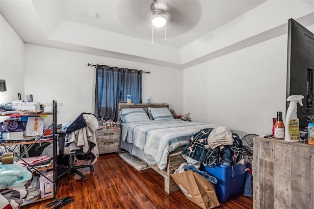 bedroom featuring a tray ceiling, ceiling fan, and dark wood-type flooring