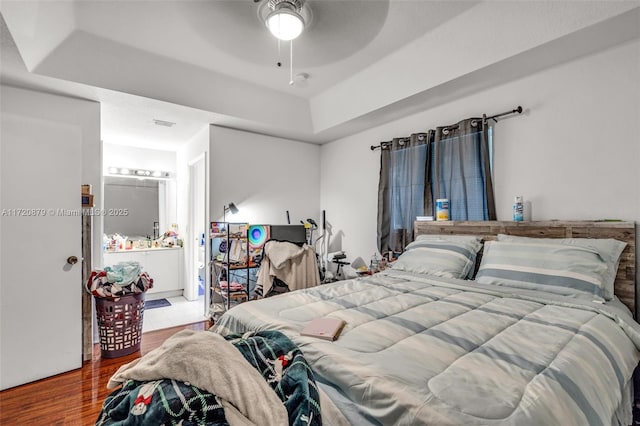 bedroom featuring ceiling fan, a raised ceiling, and wood-type flooring