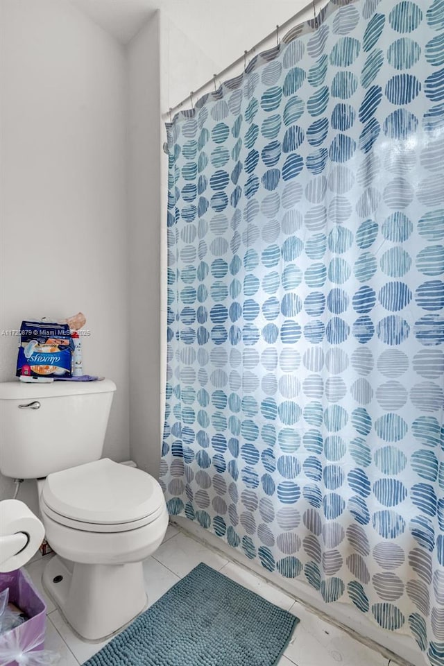 bathroom with toilet, tile patterned floors, and curtained shower