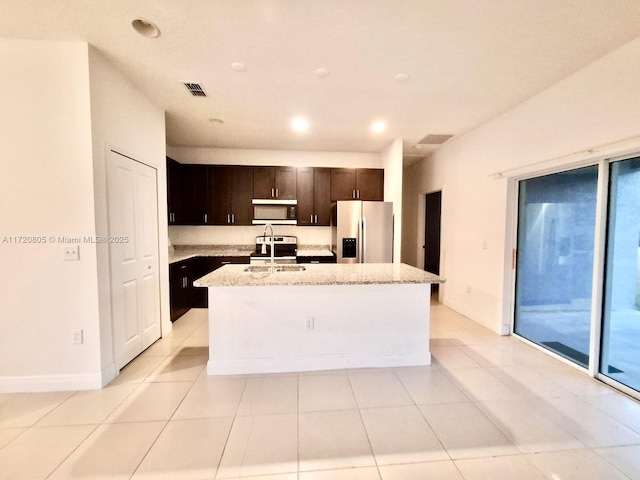 kitchen with a kitchen island with sink, sink, light tile patterned flooring, and appliances with stainless steel finishes