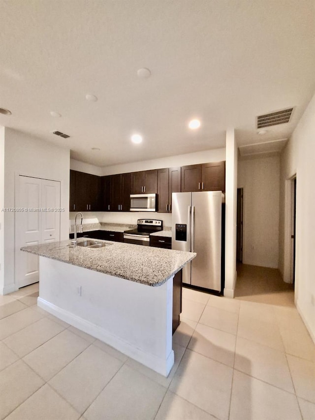 kitchen with appliances with stainless steel finishes, an island with sink, light tile patterned floors, and sink