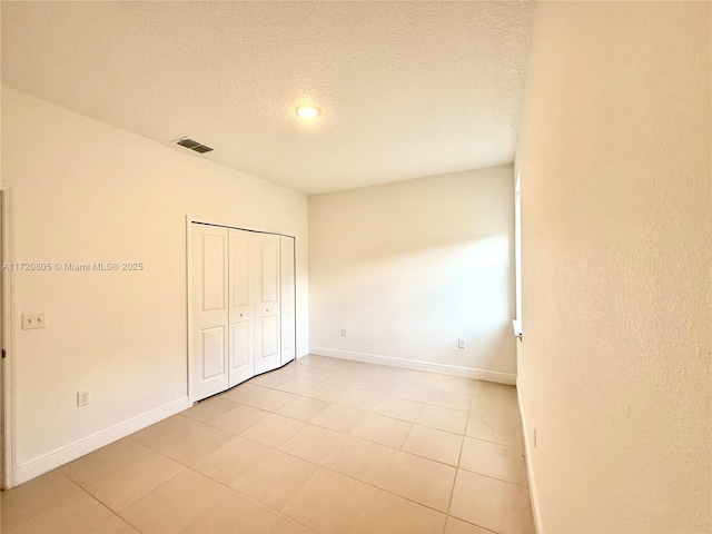 unfurnished bedroom with a textured ceiling, a closet, and light tile patterned flooring