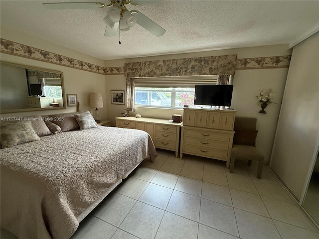 tiled bedroom with ceiling fan and a textured ceiling