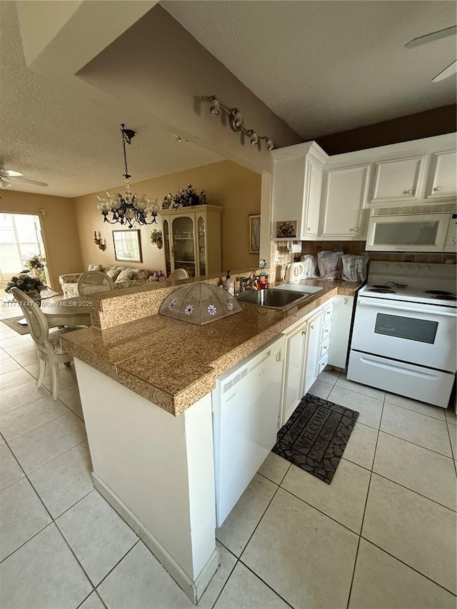 kitchen featuring kitchen peninsula, white cabinetry, sink, and white appliances