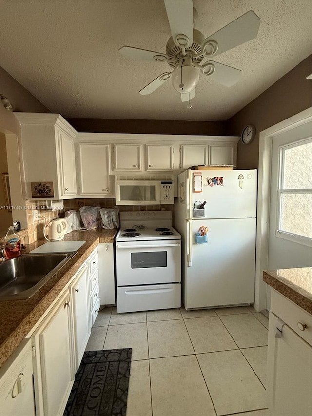 kitchen with white cabinets, white appliances, sink, and light tile patterned floors