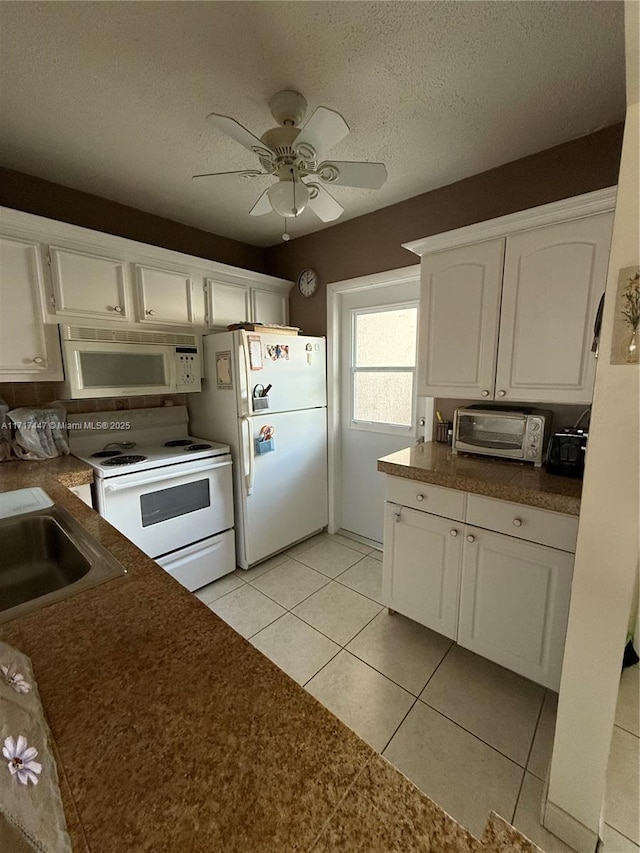 kitchen with white appliances, a textured ceiling, ceiling fan, light tile patterned floors, and white cabinets