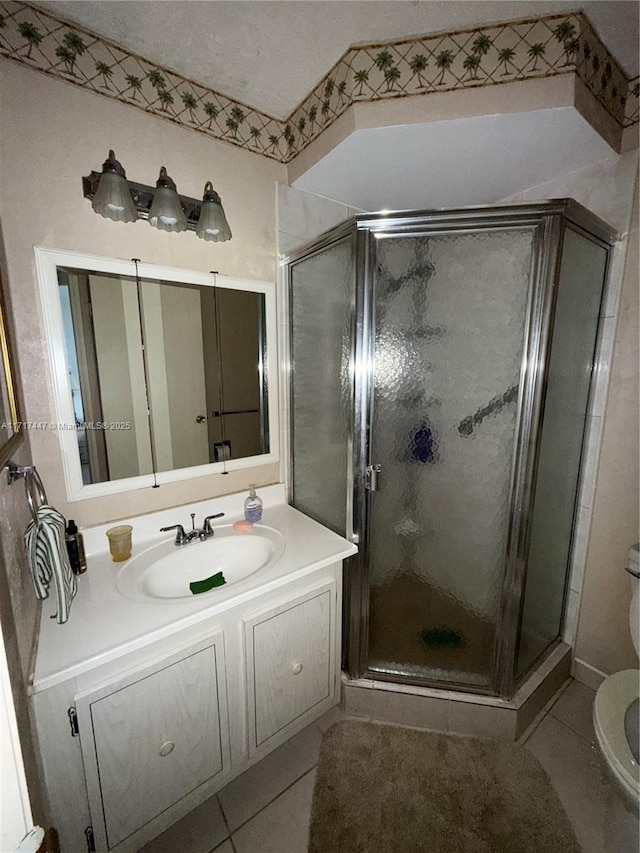 bathroom featuring tile patterned flooring, vanity, toilet, and walk in shower