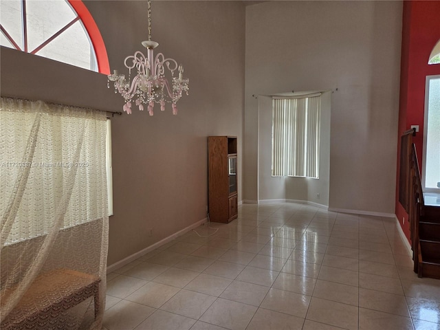 foyer entrance featuring light tile patterned floors, a notable chandelier, and a towering ceiling