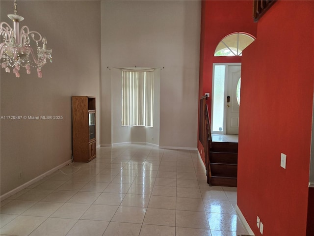 tiled entrance foyer featuring an inviting chandelier and a towering ceiling