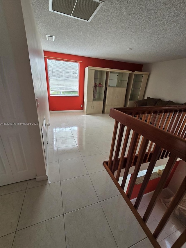 hallway featuring light tile patterned floors and a textured ceiling