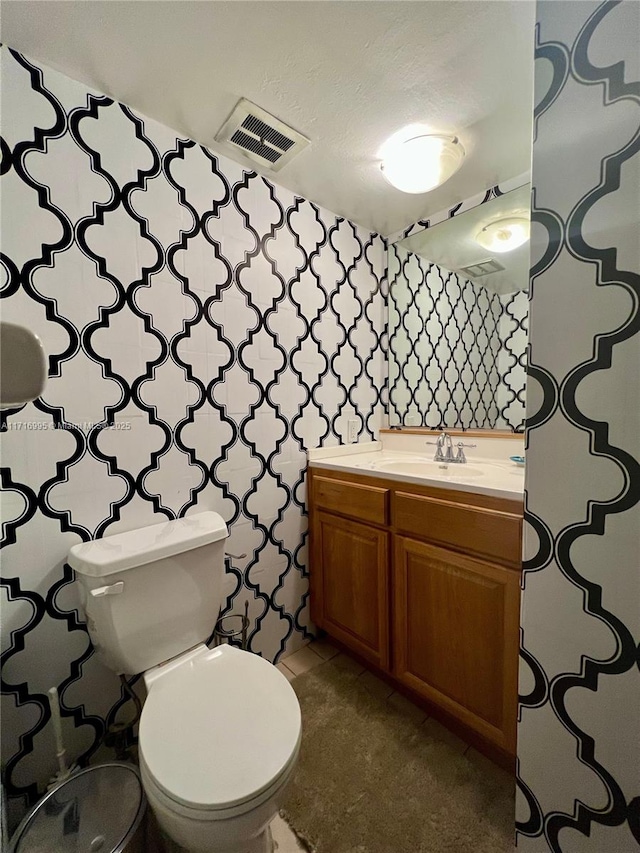 half bathroom with vanity, toilet, and visible vents