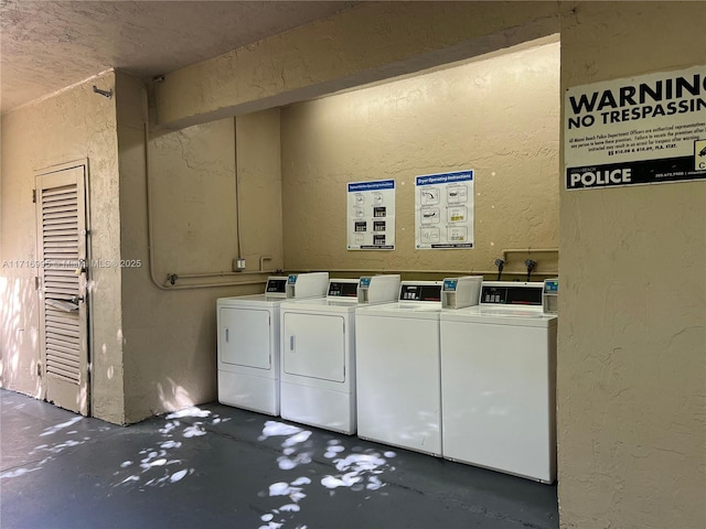 community laundry room featuring a textured wall and separate washer and dryer