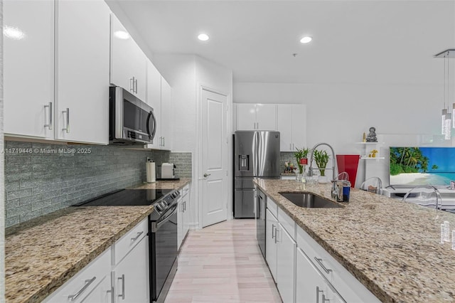 kitchen featuring sink, decorative backsplash, appliances with stainless steel finishes, light stone counters, and white cabinetry