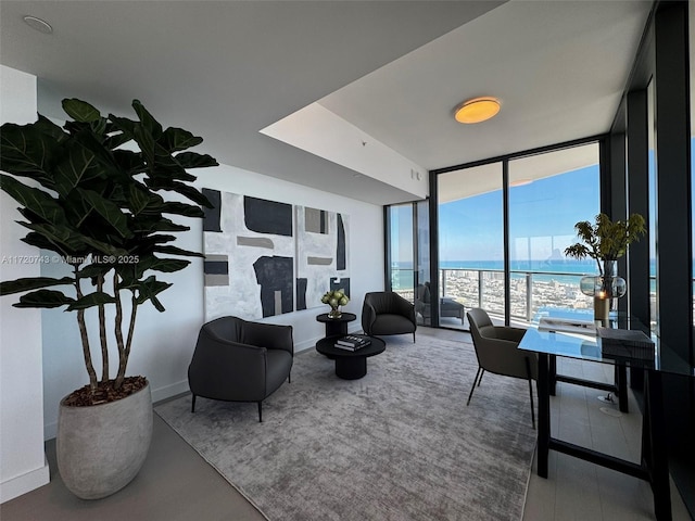 living area with a water view, baseboards, and a wall of windows