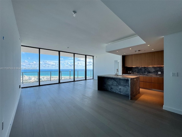 kitchen with tasteful backsplash, brown cabinetry, expansive windows, open floor plan, and modern cabinets