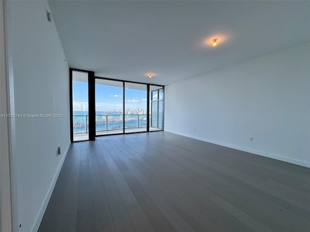 unfurnished room featuring baseboards, floor to ceiling windows, and dark wood finished floors