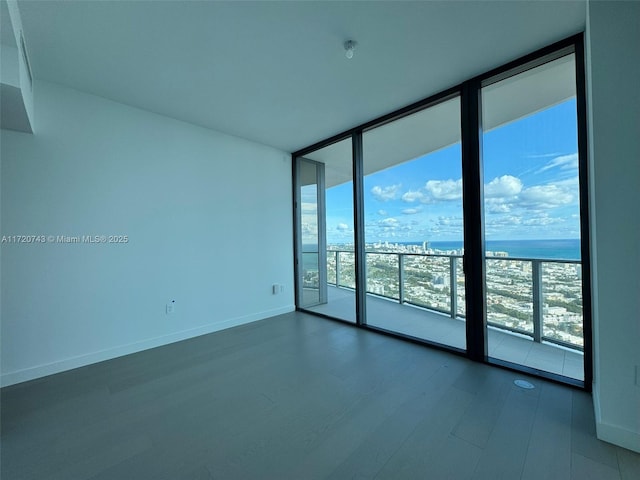 empty room featuring baseboards, floor to ceiling windows, and dark wood finished floors