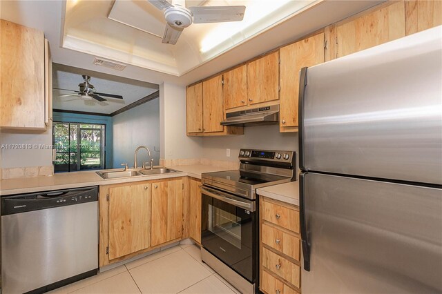 kitchen with ceiling fan, sink, stainless steel appliances, a raised ceiling, and light tile patterned flooring