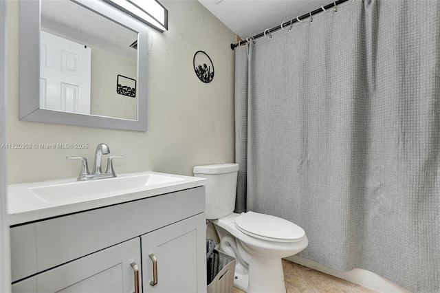 bathroom with tile patterned flooring, vanity, a textured ceiling, and toilet