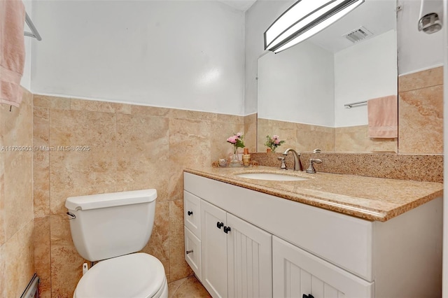 bathroom with vanity, toilet, and tile walls