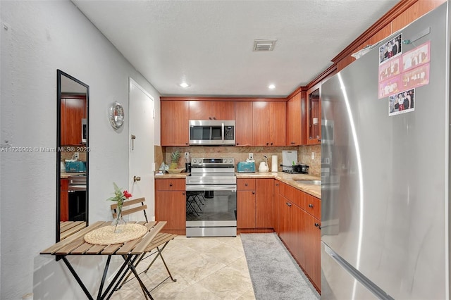 kitchen featuring light tile patterned floors, backsplash, and appliances with stainless steel finishes