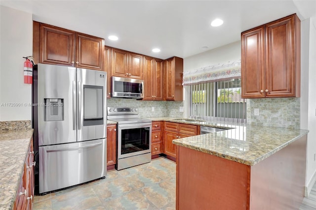 kitchen with appliances with stainless steel finishes, decorative backsplash, sink, kitchen peninsula, and light stone counters