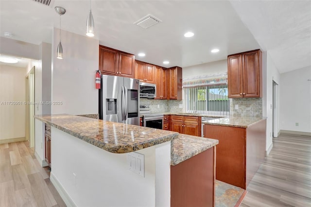 kitchen featuring tasteful backsplash, a center island, pendant lighting, appliances with stainless steel finishes, and light stone counters