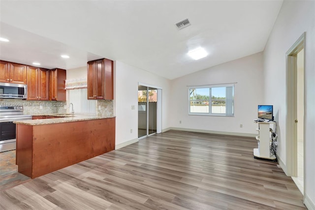 kitchen with vaulted ceiling, stainless steel appliances, kitchen peninsula, and light wood-type flooring