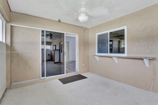 view of exterior entry featuring ceiling fan and a patio area