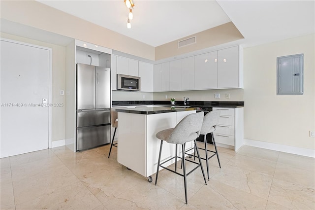 kitchen featuring a kitchen bar, electric panel, white cabinets, and stainless steel appliances